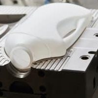 Bidon en plastique blanc en cours de fabrication sur un moule industriel en métal.