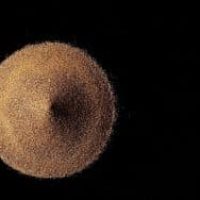 Amas de fines particules beige formant une sphère sur fond noir.